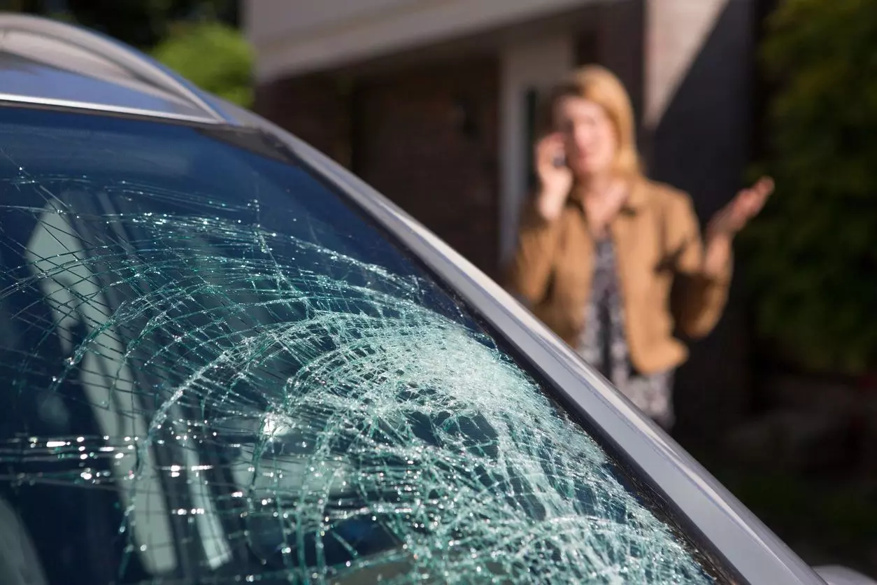 A woman on the phone in front of a car.